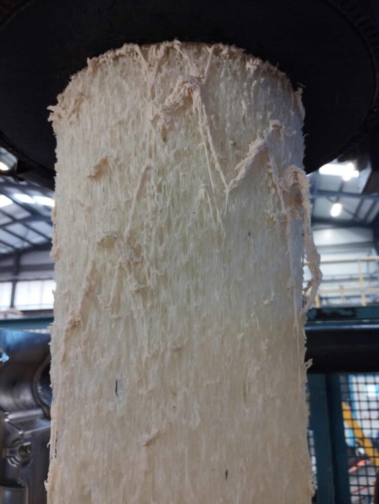 Primo piano di materiale plastico grezzo dopo l'utilizzo di un composto di spurgo per materie plastiche, che mostra i risultati della rimozione del carbonio e della pulizia dell'estrusore.